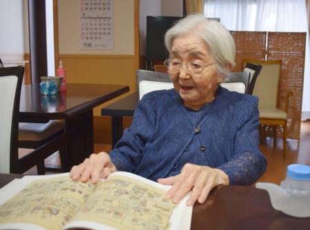 　画文集を手に、自身の体験を語る仏画家豊田和子さん＝７月、神戸市中央区