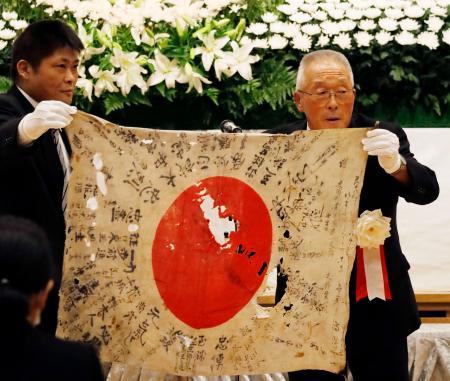 　返還された日章旗を手にする菅田信博さん（右）と工藤公督さん＝１３日午前、北海道当麻町