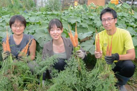 　収穫したニンジンを手にする岩本菜々さん（中央）ら＝７日、東京都八王子市