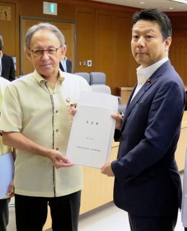 　本田太郎防衛副大臣（右）に要請書を手渡す沖縄県の玉城デニー知事＝２２日午後、防衛省