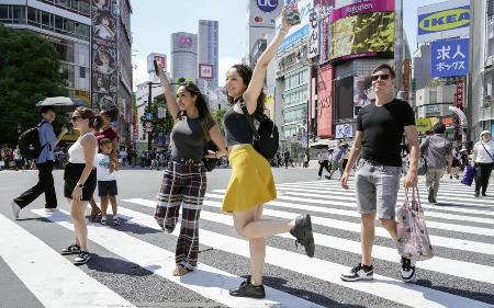 　東京・渋谷駅前で、青信号でダッシュしてスクランブル交差点の中心に向かい、ポーズを決めて記念撮影する外国人＝２０日