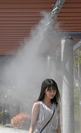 　東京・銀座でミストシャワーを浴びて涼む人＝３１日午後