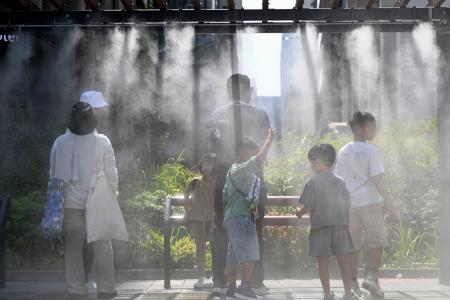 　東京・銀座でミストシャワーを浴びる人たち＝３１日午後