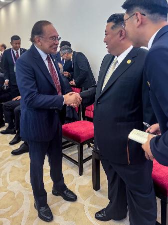 　マレーシアのアンワル首相（左）と握手を交わす北朝鮮の金正恩朝鮮労働党総書記＝３日、北京（アンワル氏のフェイスブックから、共同）