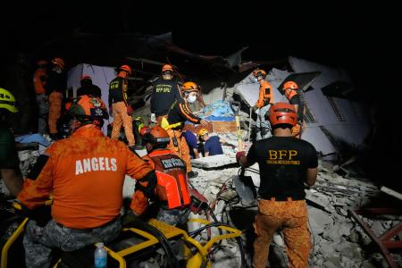 1日、フィリピン・セブ島のボゴで、倒壊した建物を調べる捜索隊員(AP=共同)