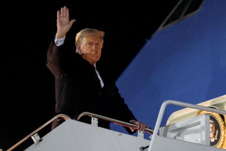 24日、米大統領専用機に乗り込む前に手を上げるトランプ大統領=ワシントン郊外(ロイター=共同)