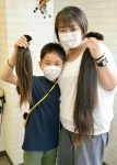 カットした髪を手にする小和瀬椛君と洋子さん＝６日、鹿児島市東千石町の「浪漫館ファース」