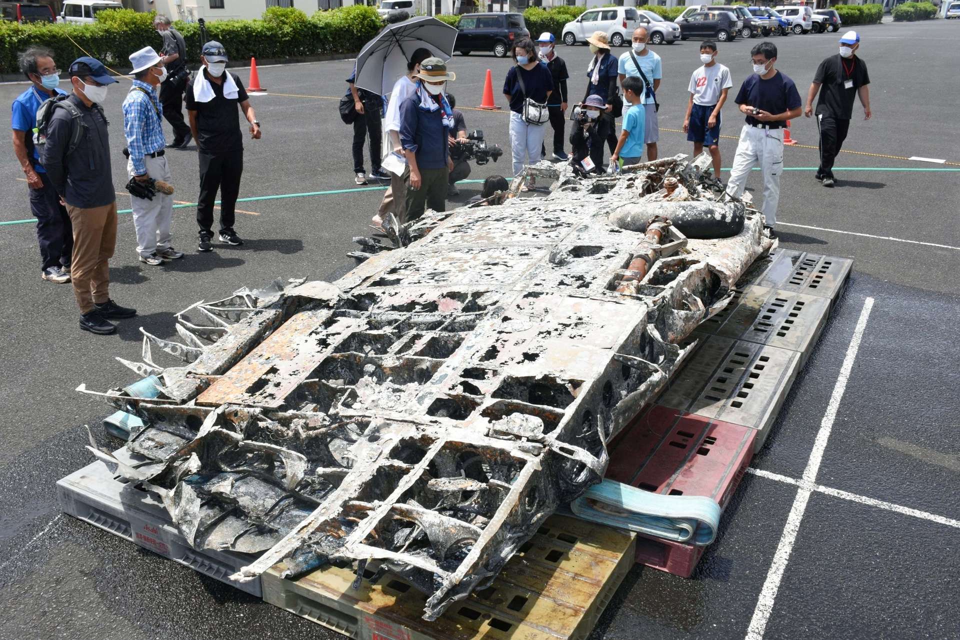 引き揚げられた左主翼の一部を見る市民ら＝１１日、西之表市鴨女町