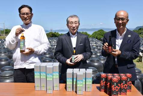 「世界自然遺産」の文字を入れた商品を手にする永田智社長（右）ら＝２７日、霧島市福山町福山の黒酢の杜