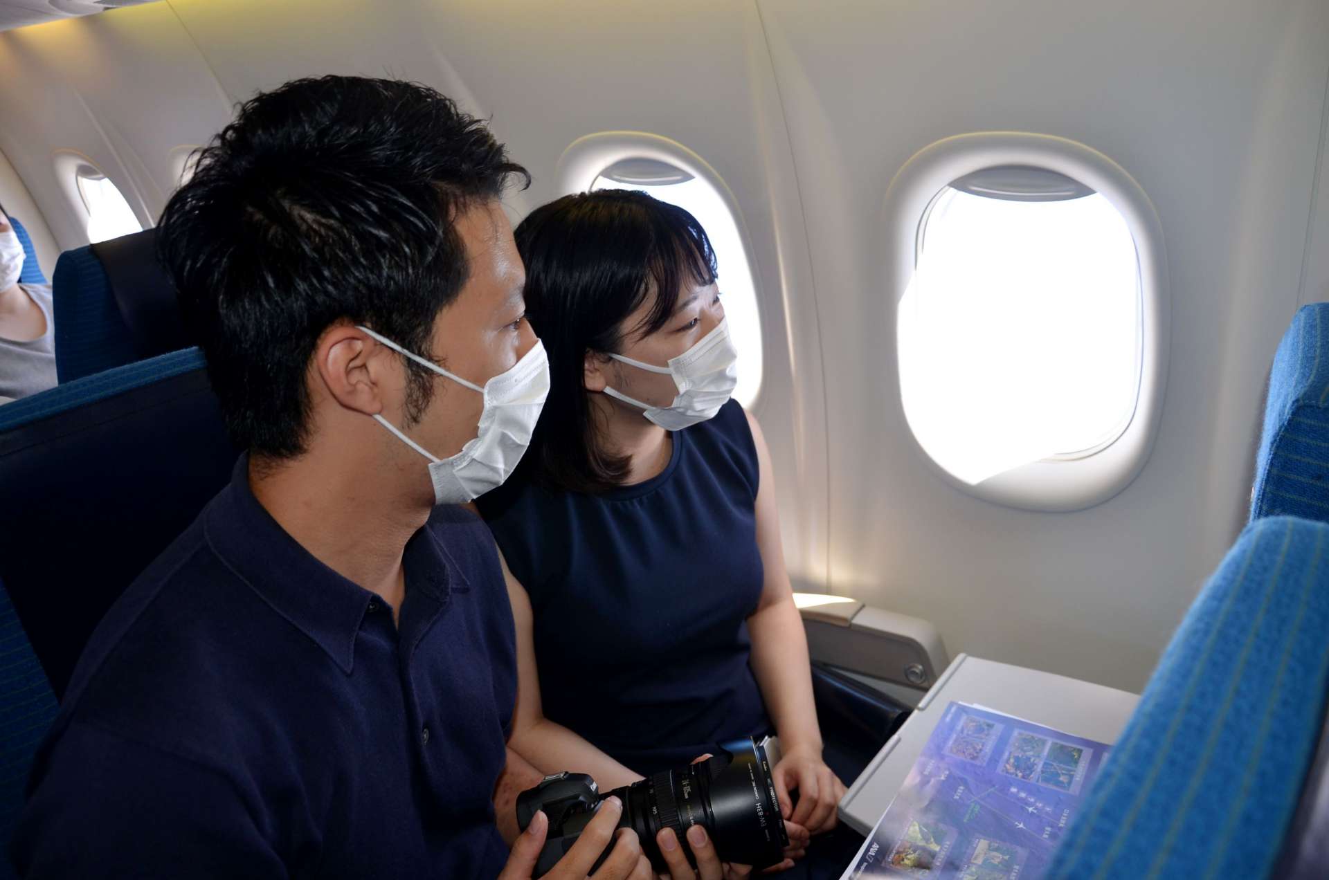 窓越しに奄美群島の眺めを楽しむ乗客＝１０日、ＡＮＡ機内