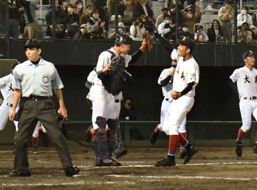 ハイタッチで勝利を喜ぶ大島の大野稼頭央選手（右）と西田心太朗選手＝２０２１年１１月７日、鹿児島市の平和リース球場