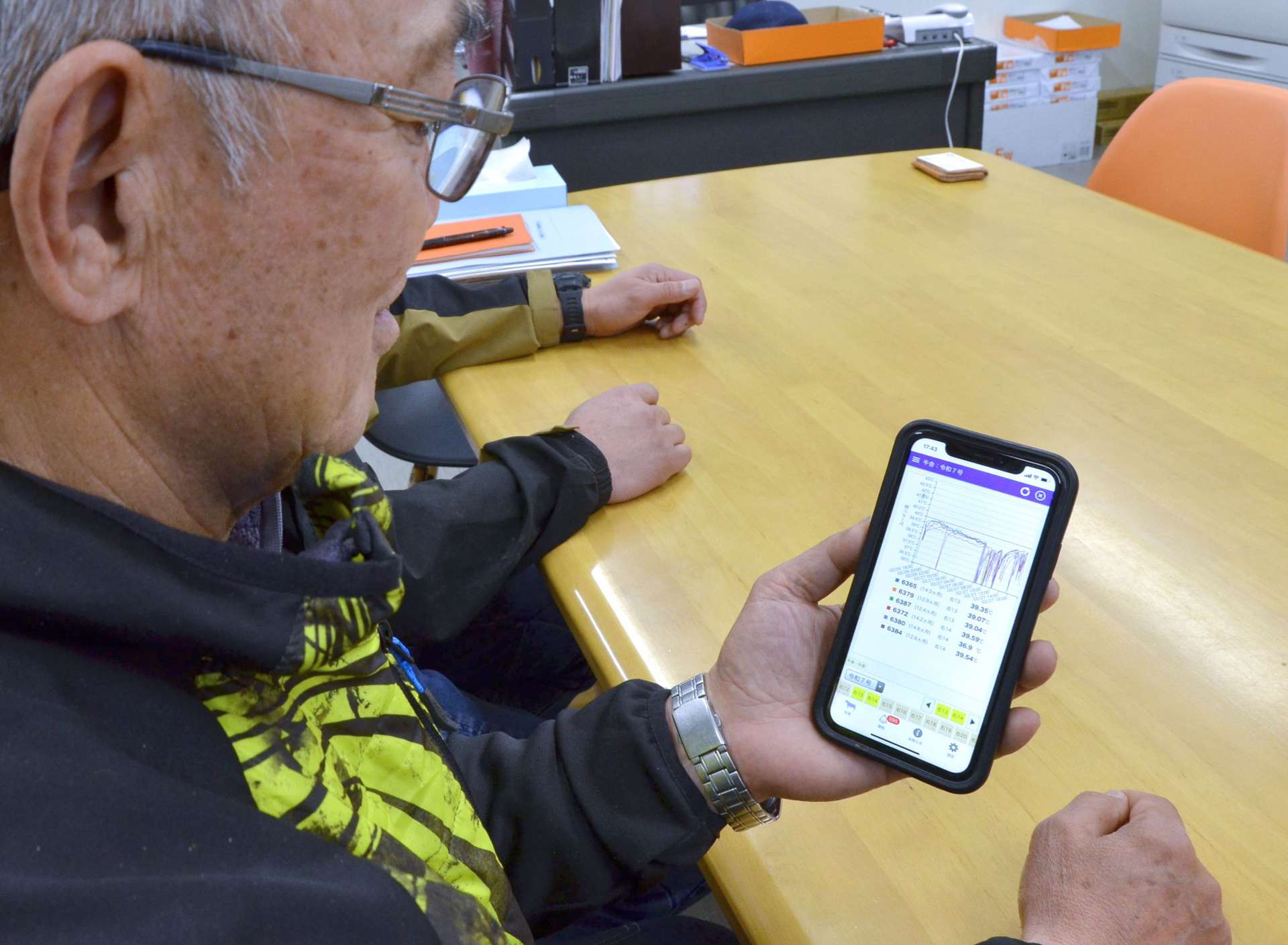 スマートフォンで牛の体温変化を確認する中山高司社長＝２月２７日、鹿屋市串良