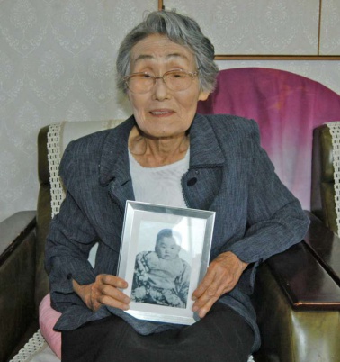 長女・望都子（もとこ）ちゃんの写真を手にする山内笑子さん＝出水市西出水町