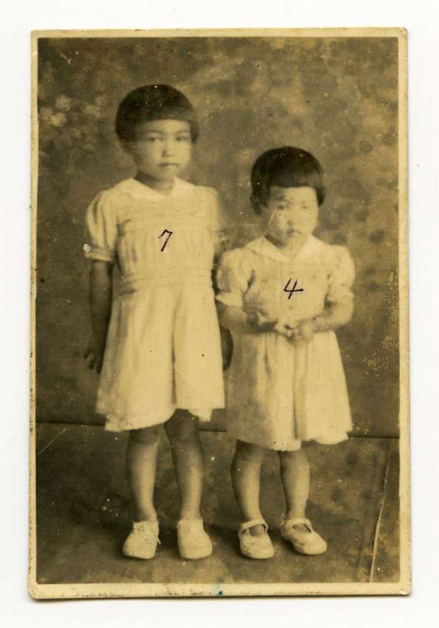父の加治木優さんが買ってくれた姉とおそろいのワンピースを着て記念写真を撮る４歳の丸野茂子さん（右）