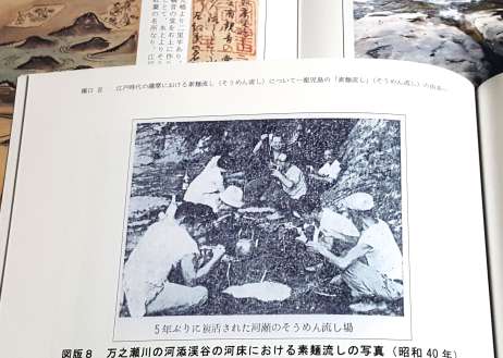 そうめん流しの歴史をまとめた橋口亘さんの論文。写真は岩盤のくぼみに入れたそうめんを、しゃがみながら食べる様子。河添渓谷で１９６５年に撮影された