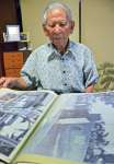 米進駐軍が鹿屋に上陸する様子を捉えた写真を見る立元良三さん＝鹿屋市高須町