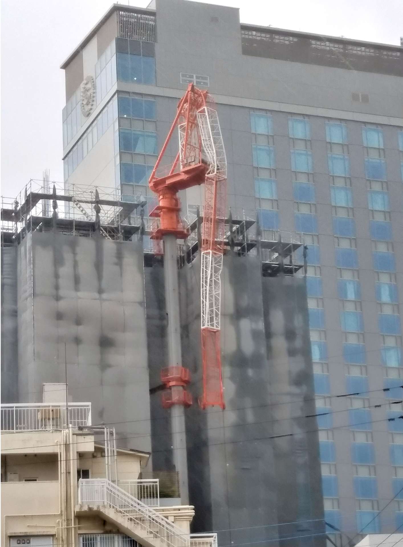 折れ曲がったマンション建設現場の作業用クレーン＝１８日午後３時半、鹿児島市高麗町