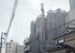 クレーンが折れ曲がり、近隣住民に避難を呼び掛ける警察官ら＝１８日午後２時４０分ごろ、鹿児島市高麗町