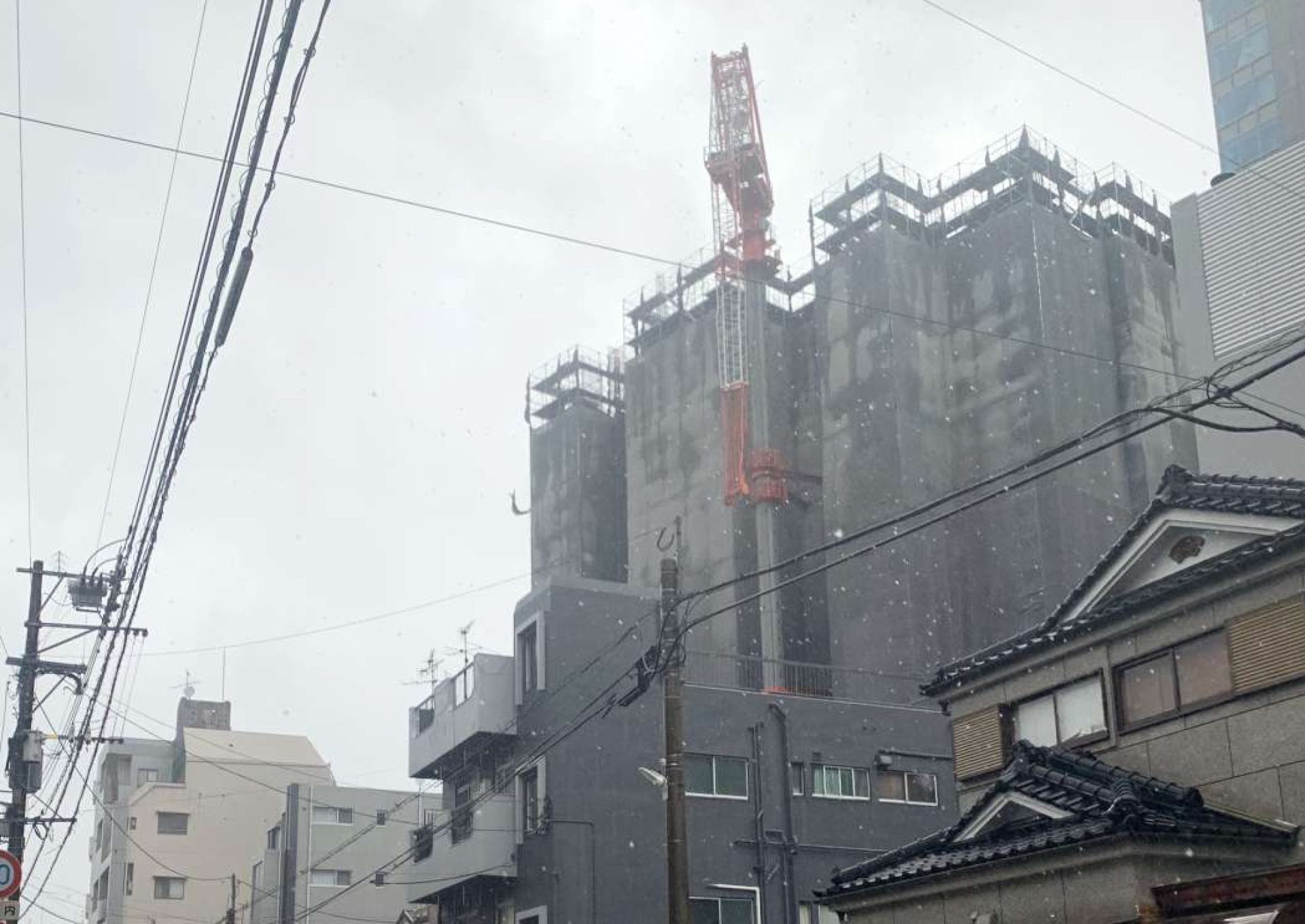クレーンが折れ曲がり、近隣住民に避難を呼び掛ける警察官ら＝１８日午後２時４０分ごろ、鹿児島市高麗町
