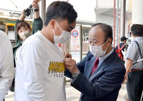 署名した人にブルーリボンを着ける市川健一さん＝１０日、鹿児島市