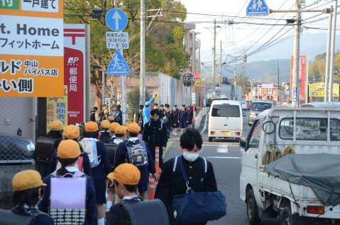 狭い路肩で児童・生徒があふれ、混雑する県道＝２日午前７時３６分、鹿児島市中山２丁目