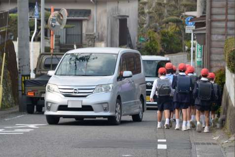 志水商店前交差点に続く坂道を下る子どもたち＝１７日午前７時４０分ごろ、鹿児島市川上町（画像の一部を加工しています）