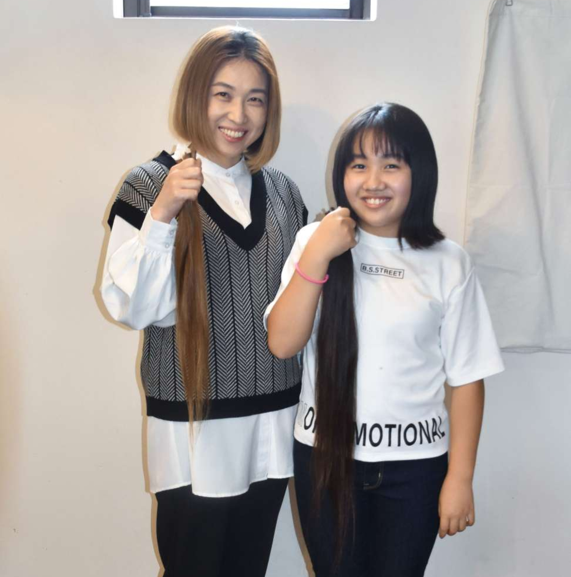 ヘアドネーションのためカットした髪を手に笑顔の松崎智美さん（左）と娘の絆笑さん＝薩摩川内市永利町
