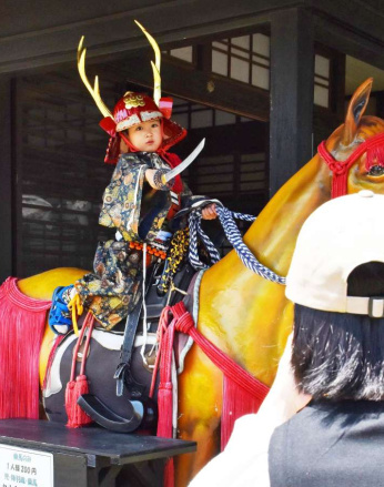 甲冑を着て、かっこよくポーズをとり記念撮影する来場者＝４月２３日、薩摩川内市の甲冑工房丸武