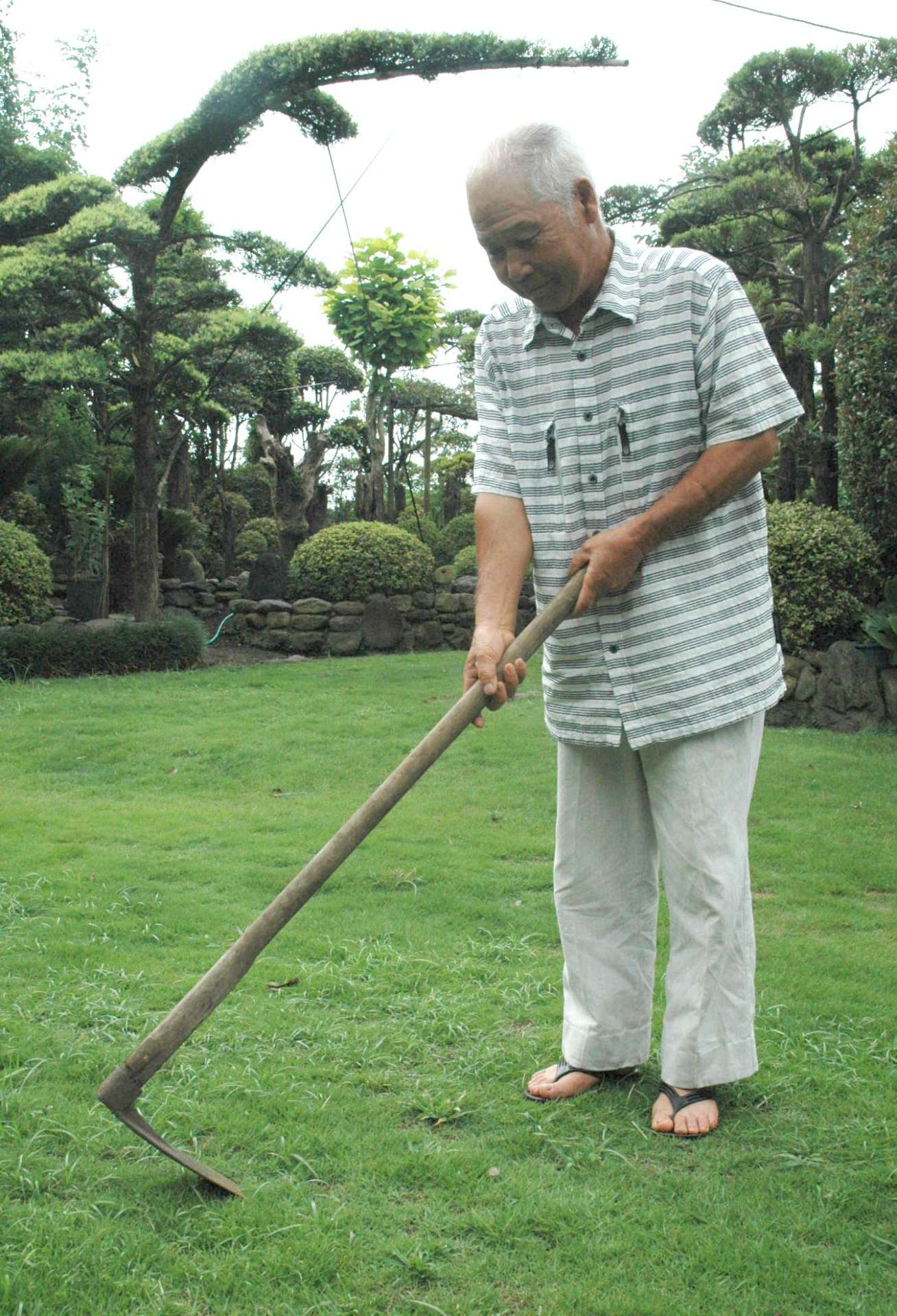 坂元和治さんは、開拓団のころから使っている山鍬を今も大事に持っている＝鹿屋市東原町