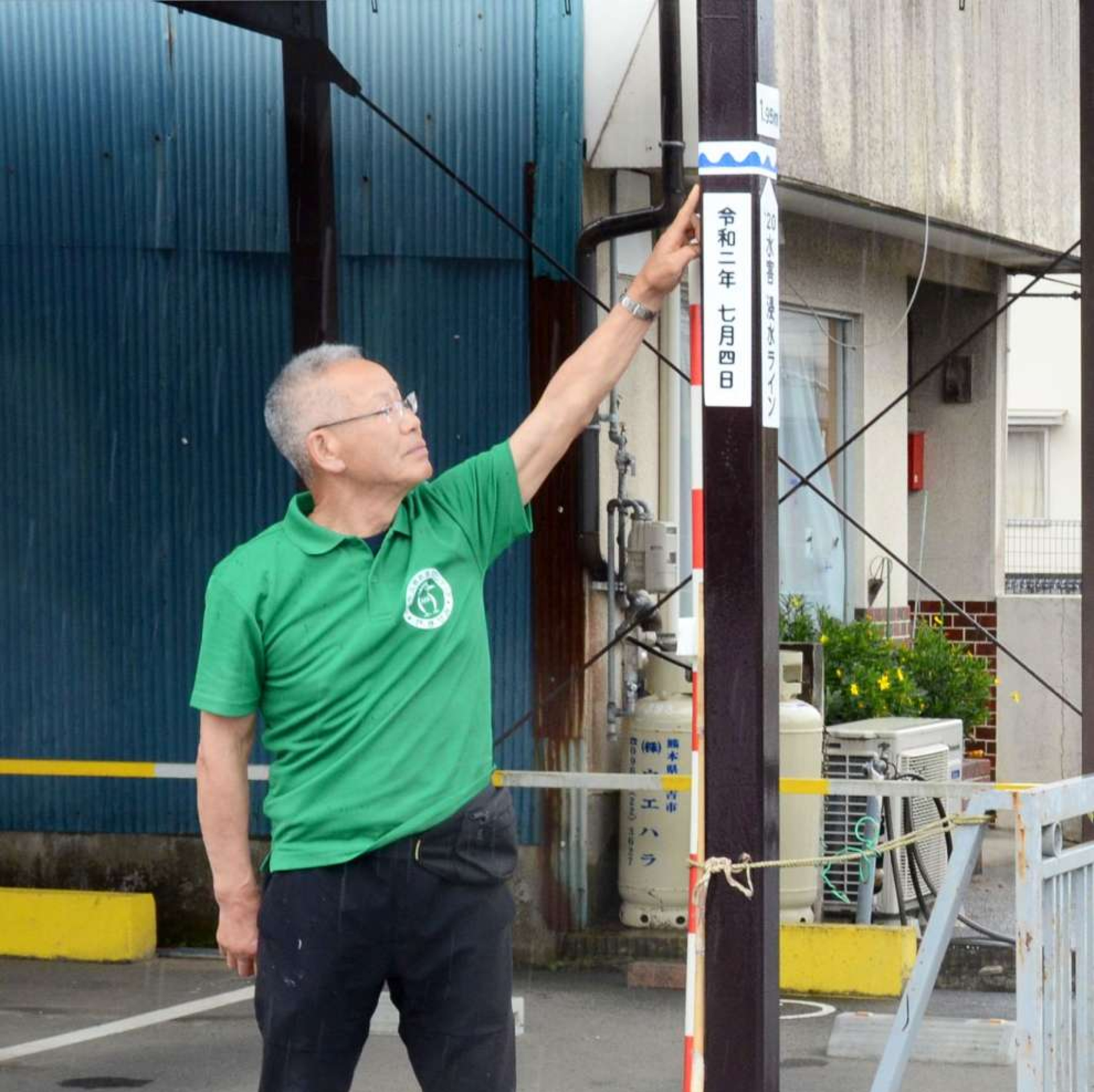 ２０２０年７月４日の豪雨で浸水した高さを示す白石忠志町内会長＝熊本県人吉市上新町