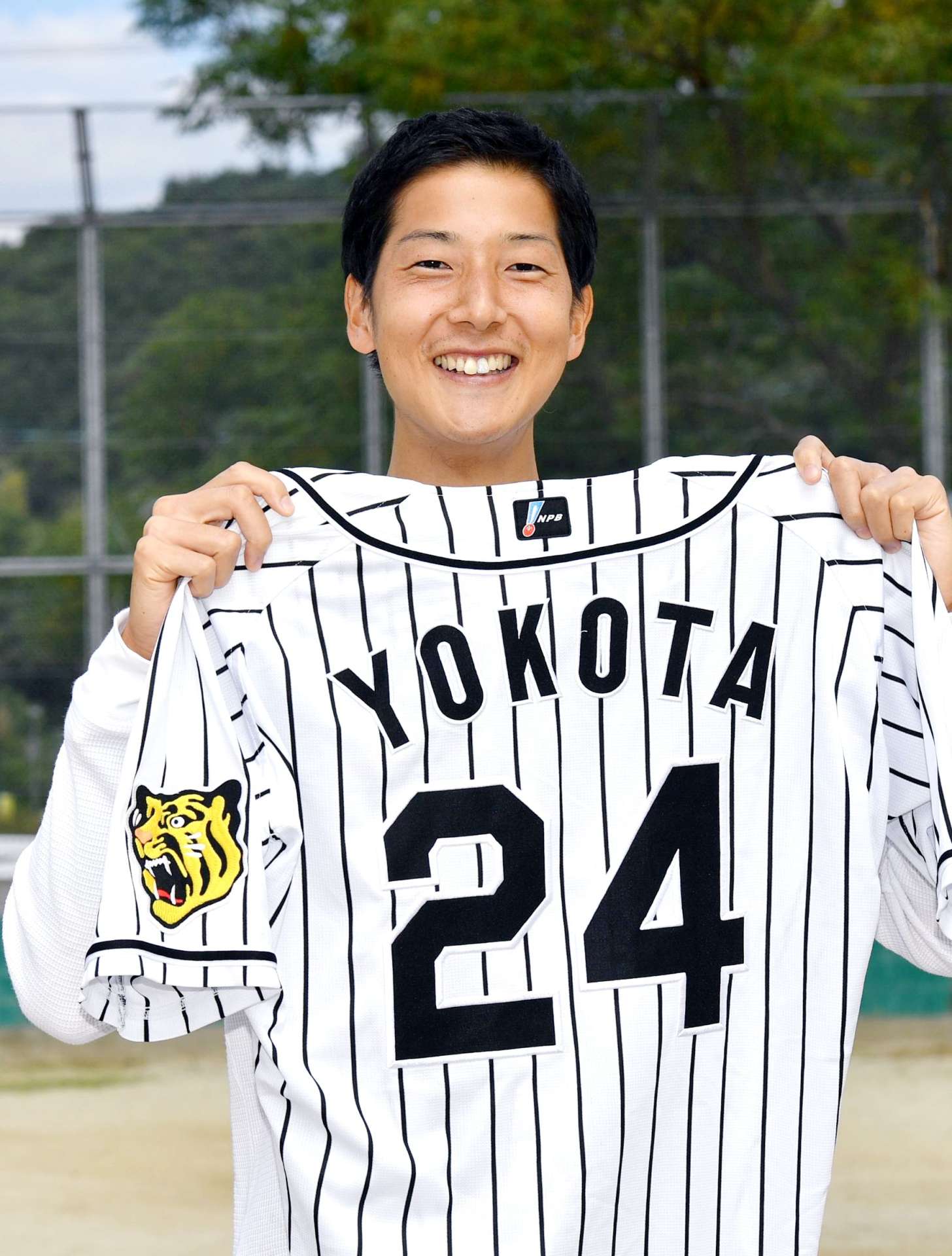 ２０２１年１０月、母校のグラウンドで阪神時代のユニホームを持つ横田慎太郎さん
