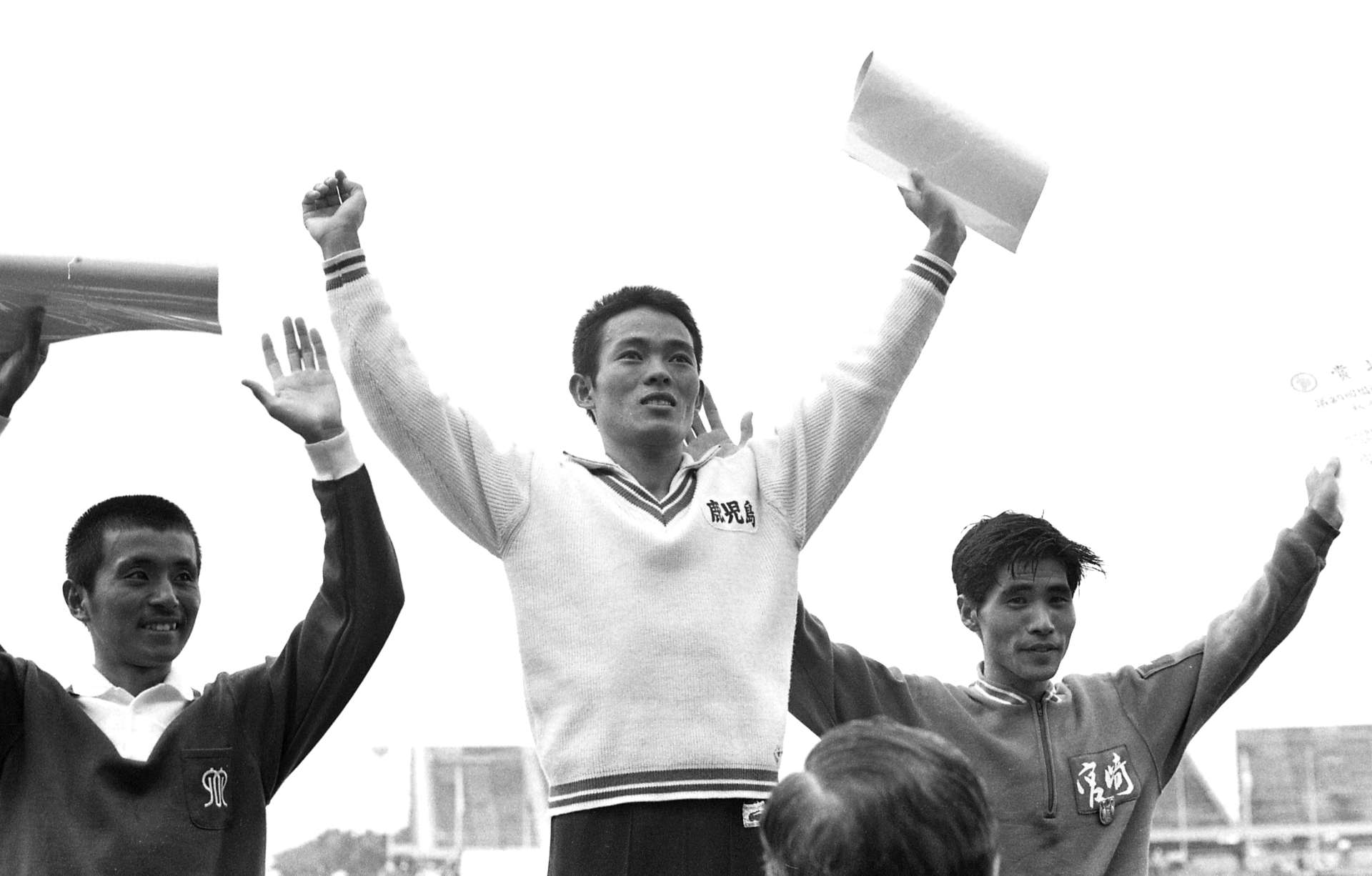 １９７２年の鹿児島国体（太陽国体）で３５キロロードレースを制し、表彰台で観衆に応える浜田安則さん（中央）＝鹿児島市の県立鴨池陸上競技場