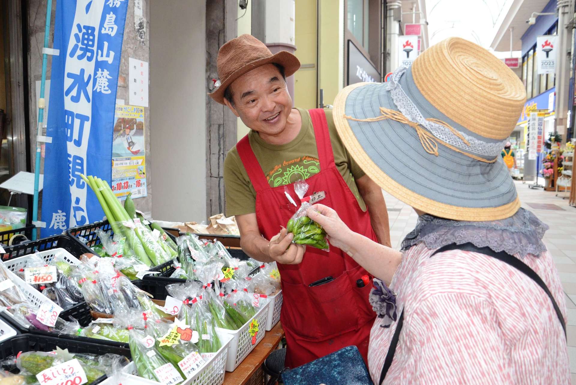 「おおきに」と声をかけ、品を手渡す井上順二さん＝鹿児島市金生町