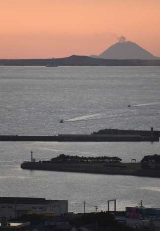 夕日でシルエットが浮かび上がった馬毛島の岳之腰。奥の島影は三島村・硫黄島＝１９日、西之表市