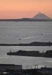 夕日でシルエットが浮かび上がった馬毛島の岳之腰。奥の島影は三島村・硫黄島＝１９日、西之表市