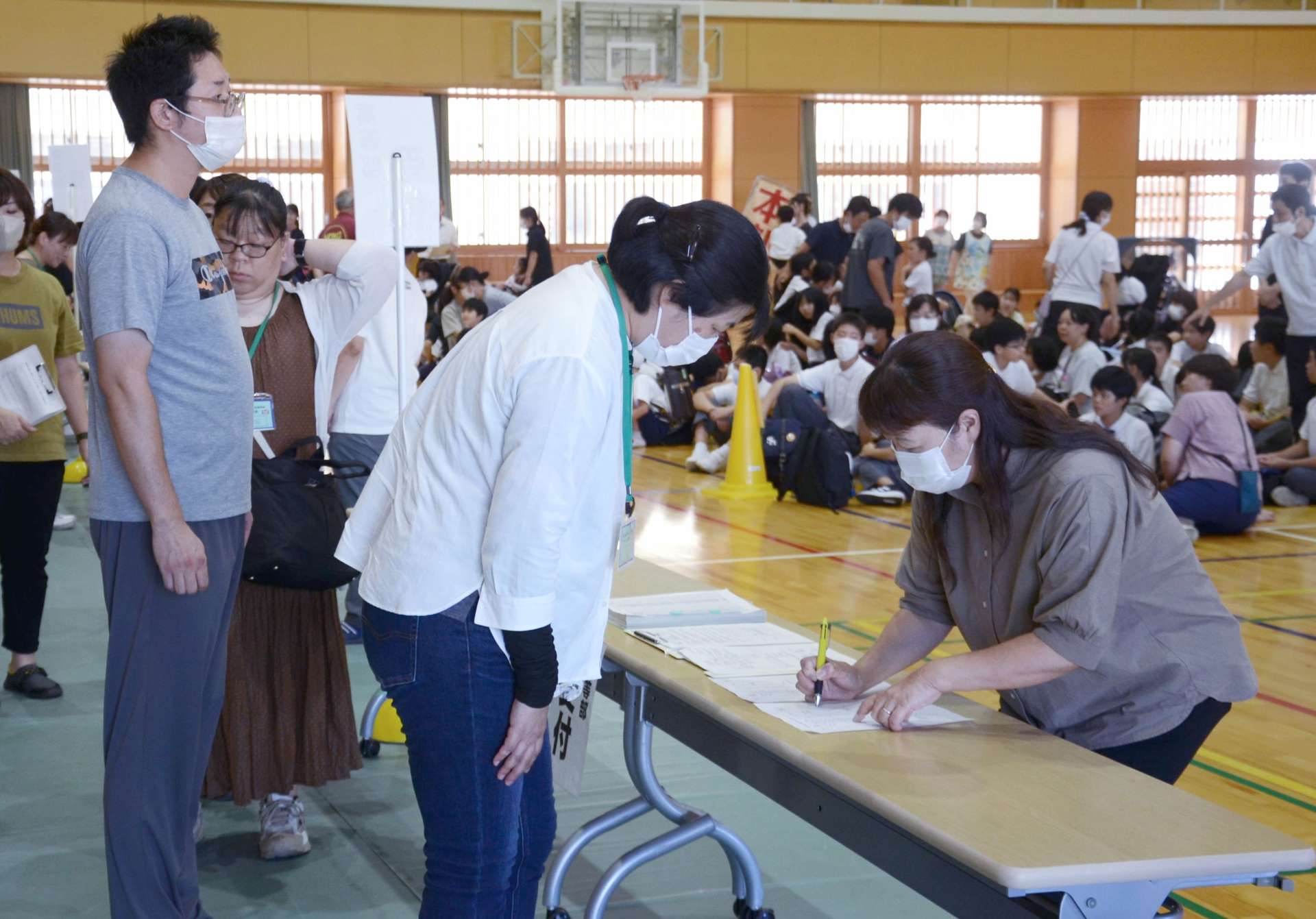 名簿を見て、迎えに来た保護者を確認する担当者＝６日、鹿児島市の鹿児島特別支援学校