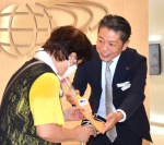 アミュプラザ鹿児島開業２０周年を記念し、来館者に花束を渡すＪＲ鹿児島シティの山崎慎介社長（中央）＝１７日、鹿児島市