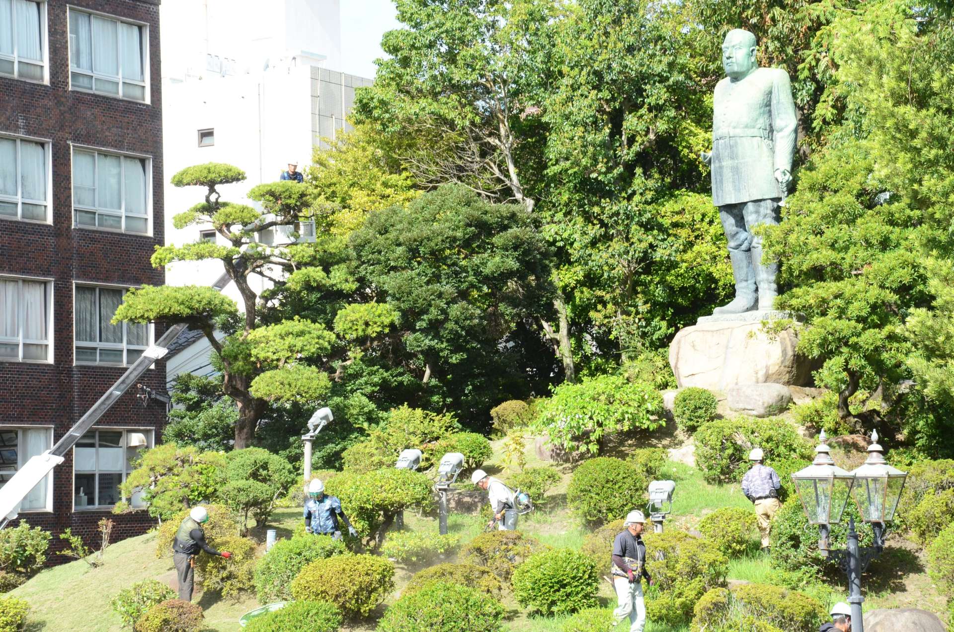西郷隆盛銅像周辺のせん定をする県造園建設業協会の会員＝１９日、鹿児島市城山町