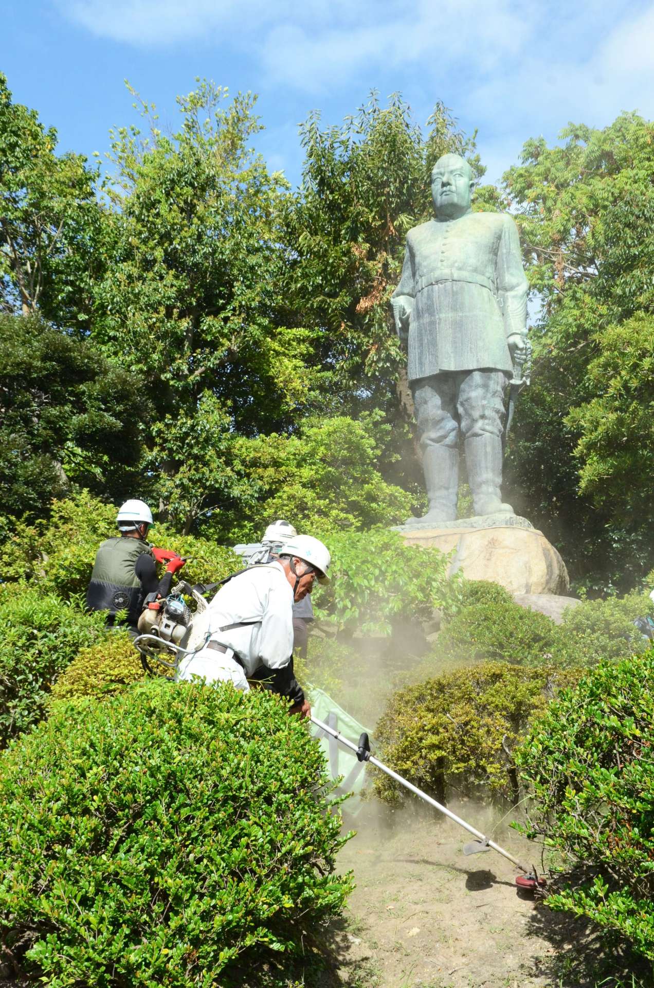 西郷隆盛銅像周辺のせん定をする県造園建設業協会の会員＝１９日、鹿児島市城山町
