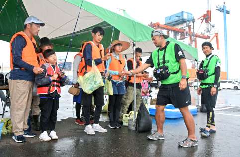 〈関連〉志布志港新若浜地区防波堤であった釣り教室に参加する家族連れ。背後にはガントリークレーンがそびえる＝志布志市志布志町安楽