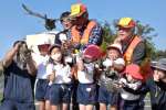 恐る恐るキジを抱え、空に放つ幼稚園児と東猟友会のメンバーら＝２７日、長島町の針尾公園