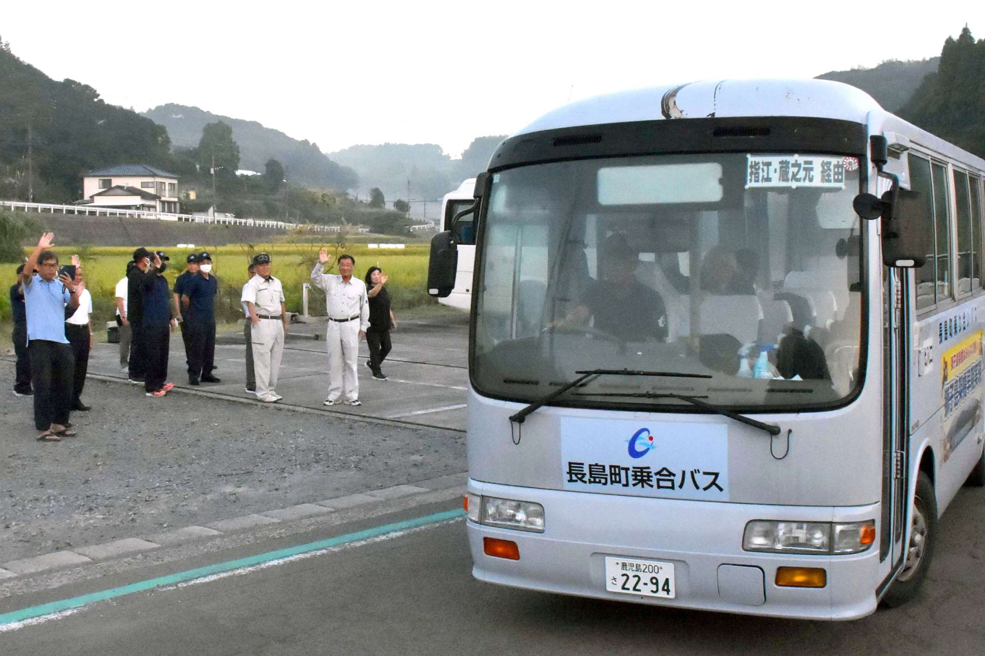 西回りでだんだん市場に向かう第１便に手を振る住民ら＝１日午前６時半ごろ、長島町平尾