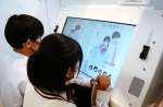 撮影した写真に落書きして楽しむカップル。男性も楽しめる機能が満載だ＝９月２７日、鹿児島市千日町のぷりタウン