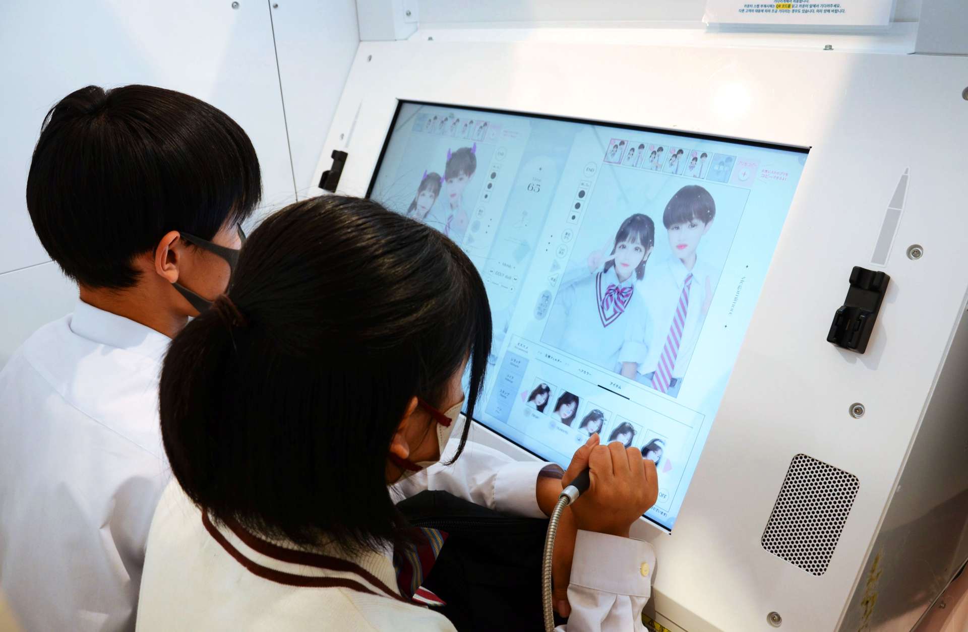 撮影した写真に落書きして楽しむカップル。男性も楽しめる機能が満載だ＝９月２７日、鹿児島市千日町のぷりタウン