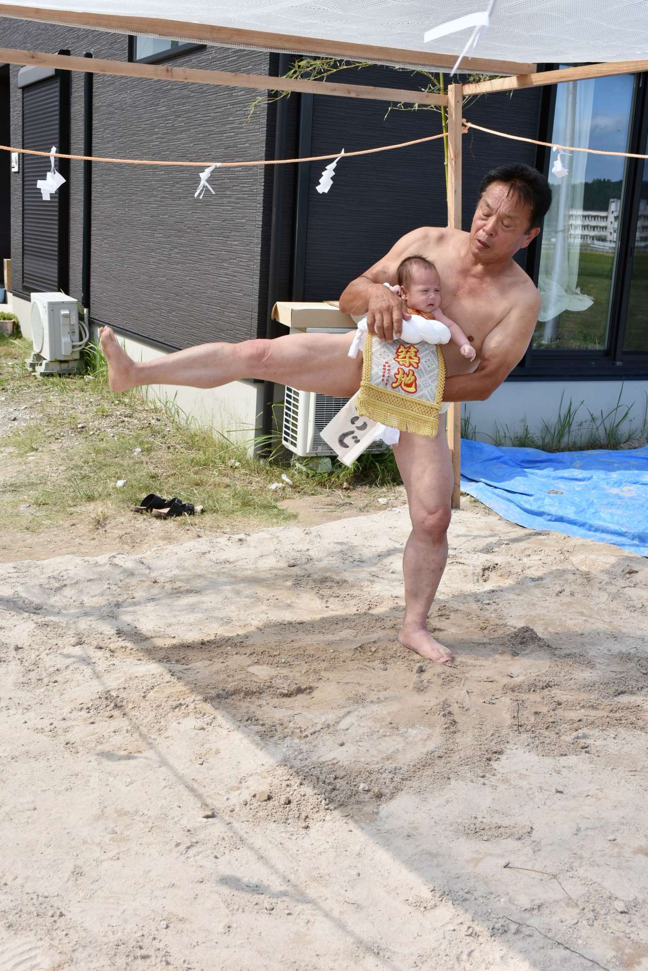 孫を抱き、赤ちゃんの土俵入りで健やかな成長を祈る橋口春男さん＝５日、伊佐市菱刈川北