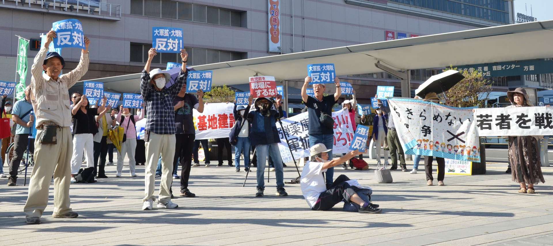 戦争に反対するメッセージを込めた横断幕などを掲げる参加者＝１３日、鹿児島市の鹿児島中央駅東口