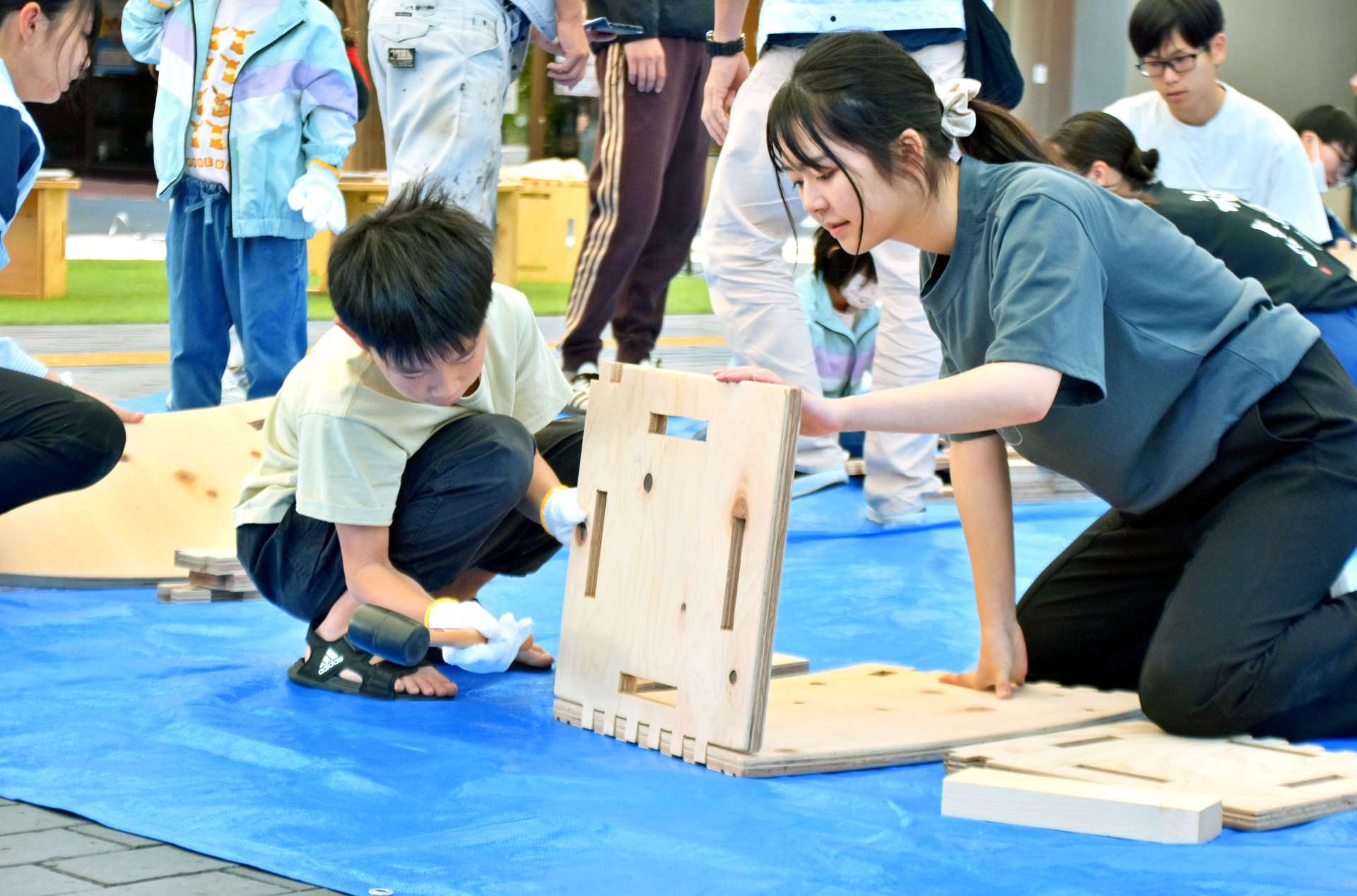 都城高専生のサポートを受け、椅子を組み立てる児童＝都城市中町の「まちなか広場」