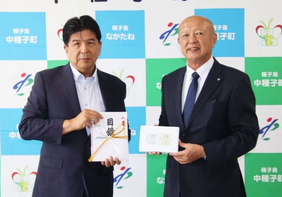 フェリーの往復乗船券を田渕川寿広町長（右）に託した市丸隆二郎社長＝２２日、中種子町役場