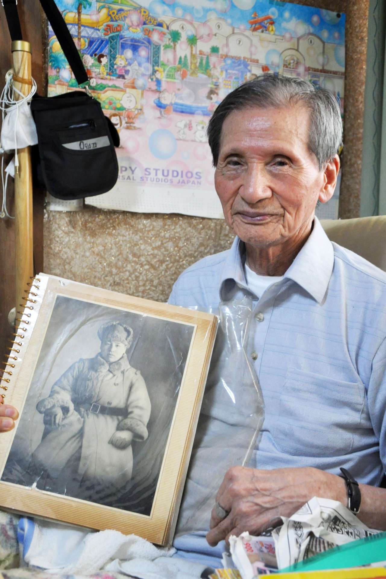 満州時代の写真を持つ緒方利光さん。体には今も手榴弾の破片１００個余りが残ったままだ＝伊佐市菱刈花北