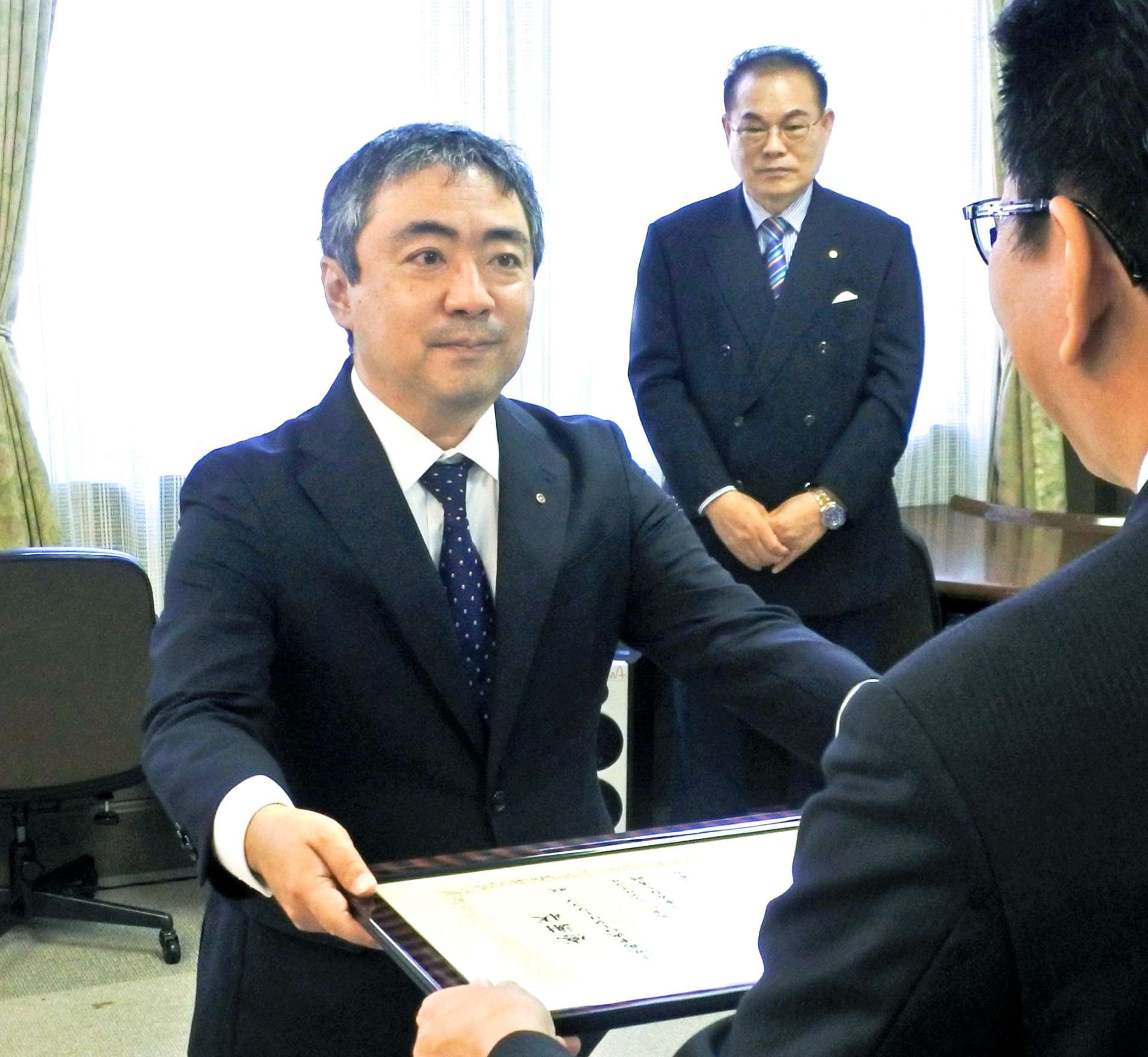 感謝状を受け取る鹿児島中央ロータリークラブの下村哲也会長とセ釜山ロータリークラブのユン・テソン会長（奥）＝５日、鹿児島市役所